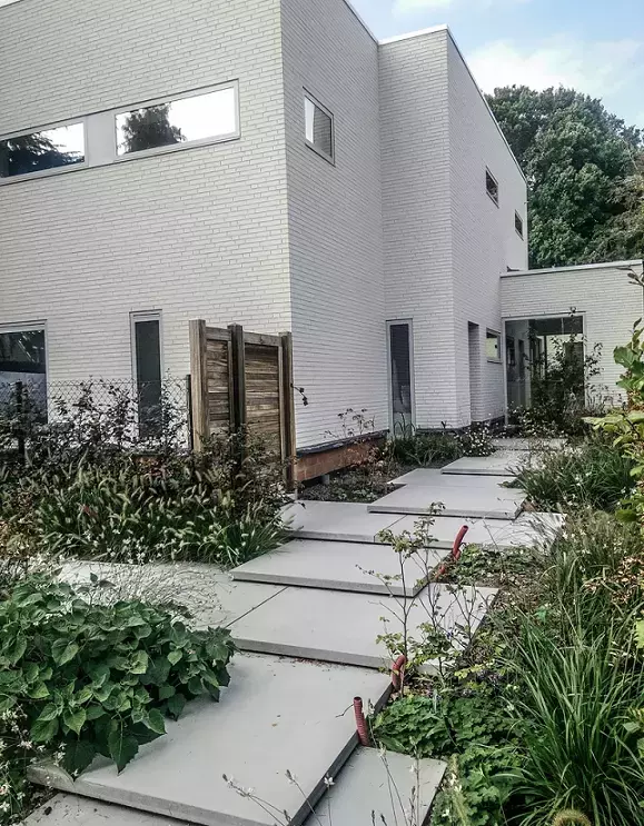 Moderne voortuin met grootformaat betonplaten als trap naar voordeur