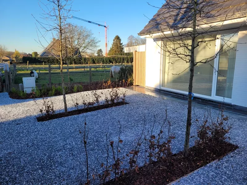 Voortuin met grind, plantenstrook en bomen