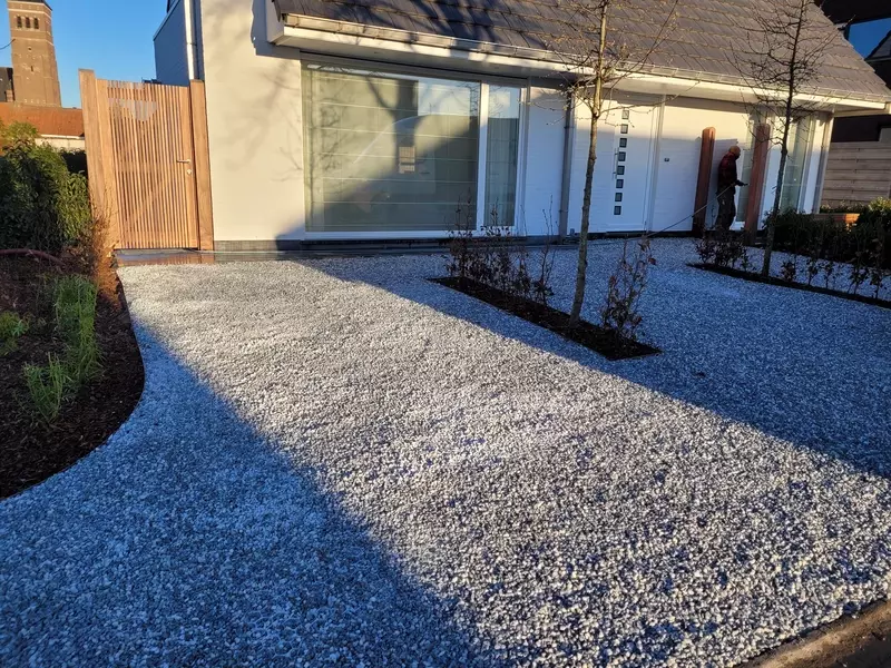 Voortuin met grind, plantenstrook en bomen