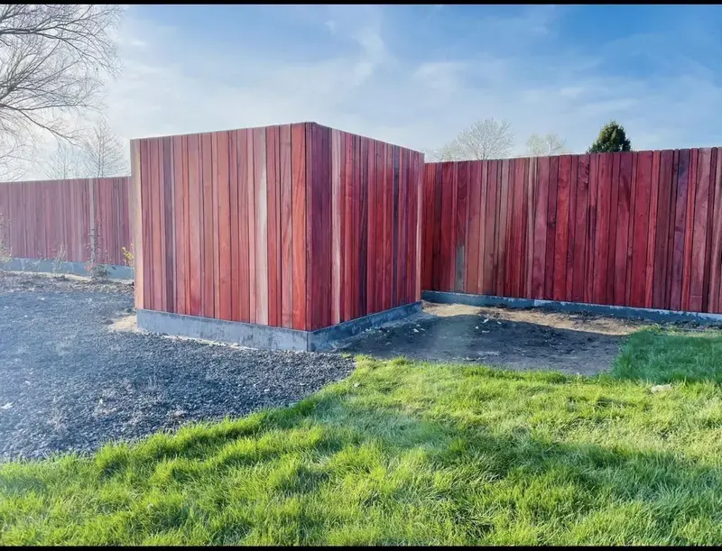 Foto van houten schuttingpanelen in een tuin tegen een blauwe lucht.