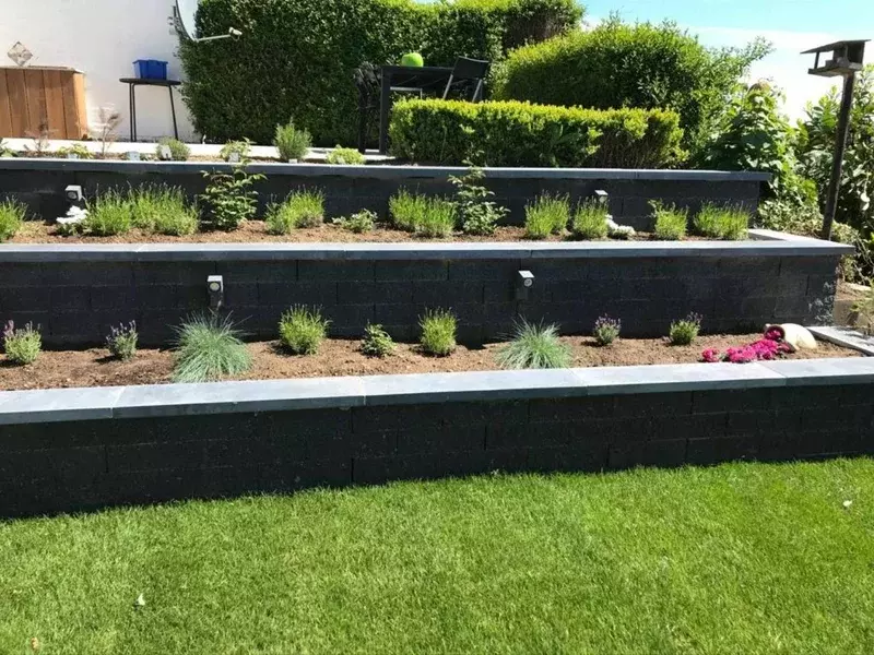 Plaatsing van Stacktonmuren in verschillende niveaus, afgewerkt met blauwe arduindekstenen