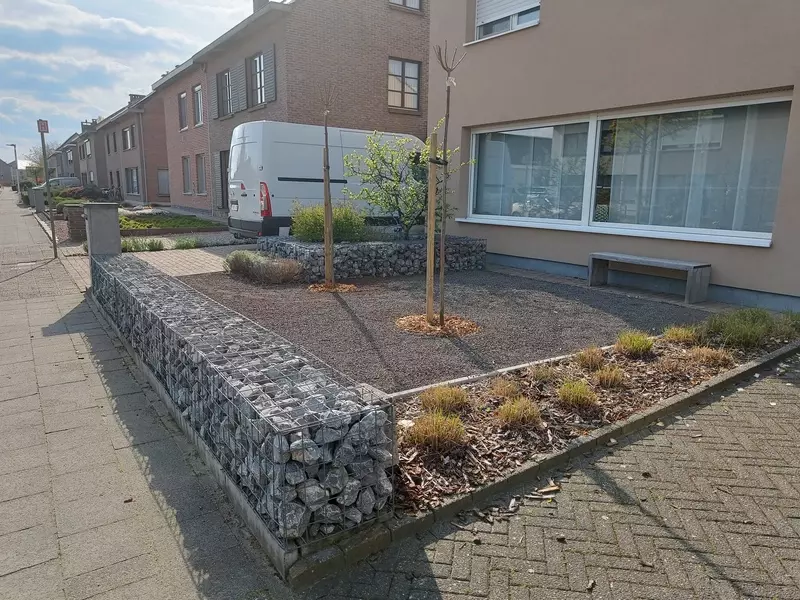 Heraanleg van een voortuin waar geopteerd is voor een water doorlatende verharding met 2 bol catalpas die voor een natuurlijke koelte vormen wanneer de zon op de voorgevel staat.