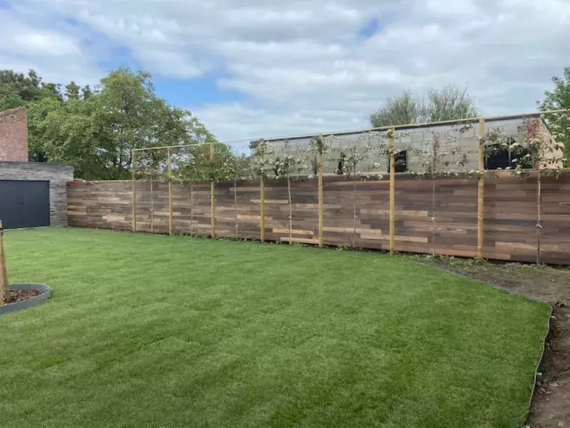 Plaatsen van een wand in padouk en aanleg tuin met grasmatten