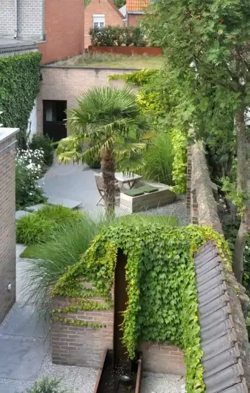 Stadstuintje met terras in blauwsteen klinkers, maatwerk zitbank in hout, waterelement in cortenstaal