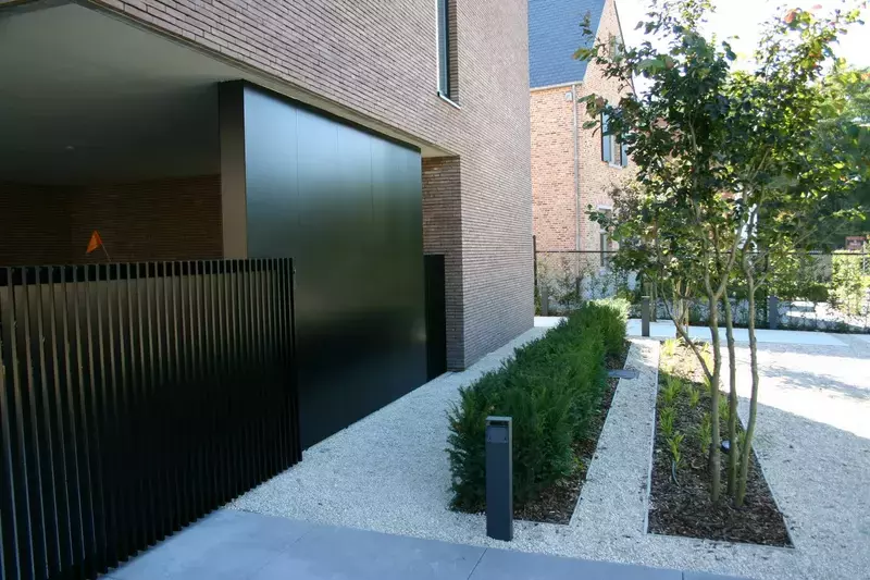 Strakke voortuin met vloerplaten van Eurodal en subtiele verlichting en een tuinpoort die in het oog springt